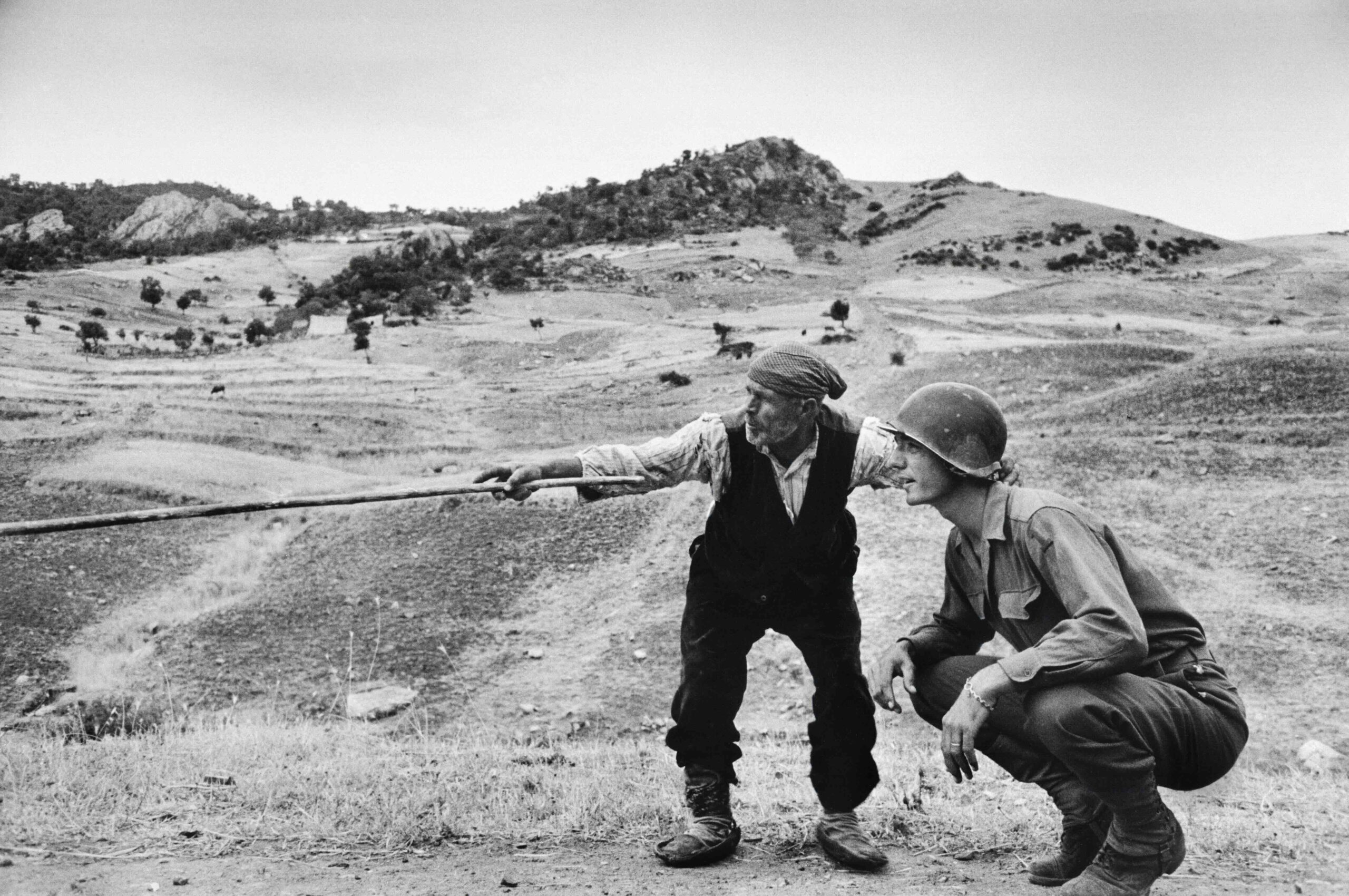 A-sicilian-peasant-telling-an-American-officer-which-way-the-Germans-had-gone-near-Troina-Italy-August-1943.-Robert-Capa_International-Center-of-Photography_Magnum-Photos